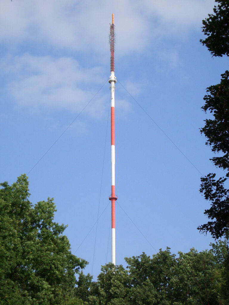 Der hoch in den Himmel aufragende Sendemast des Senders Scholzplatz vor blauem Himmel.