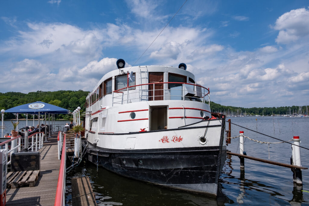 Frontaler Blick auf das Restaurant-Schiff Alte Liebe, das am Havelufer ankert.