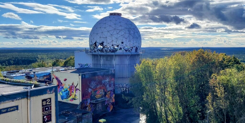 Blick auf einen der langsam verfallenden Türme der Abhörstation mit weißer Antennenkuppel.
