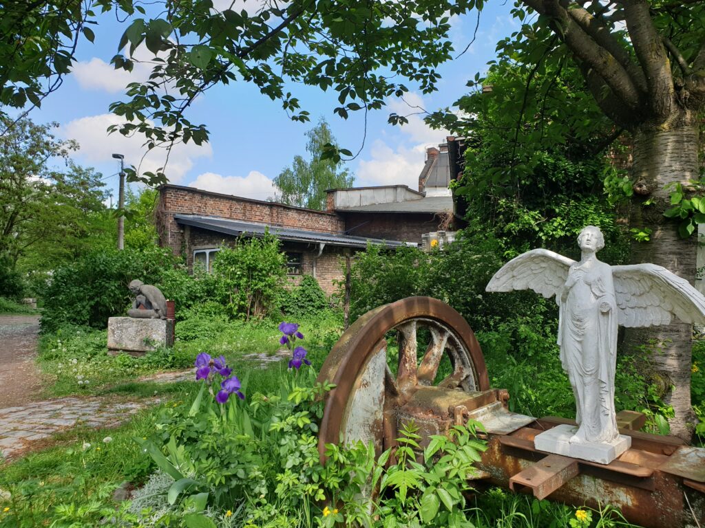 Außenansicht der BLO Ateliers mit verschiedenen Pflanzen und einer Engelsstatue