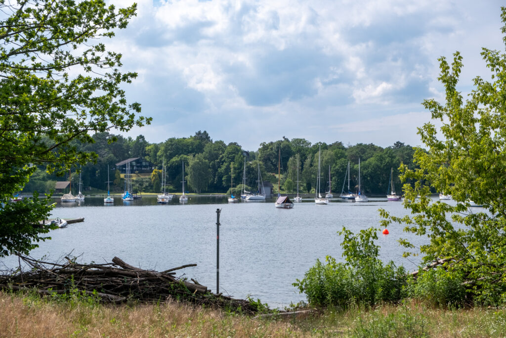 Blick vom gegenüberliegenden Ufer auf Boote, die vor der Insel Schwanenwerder ankern.