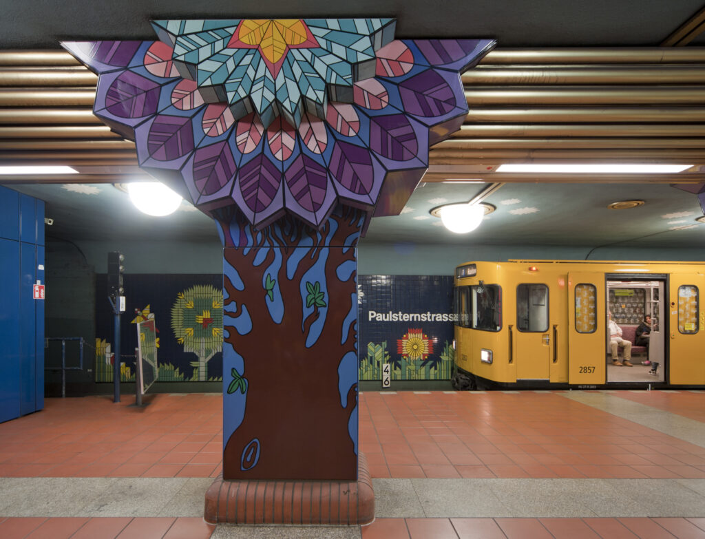 Farbige Kacheln mit Mustern in der U-Bahnstation. Eine Bahn fährt ein.