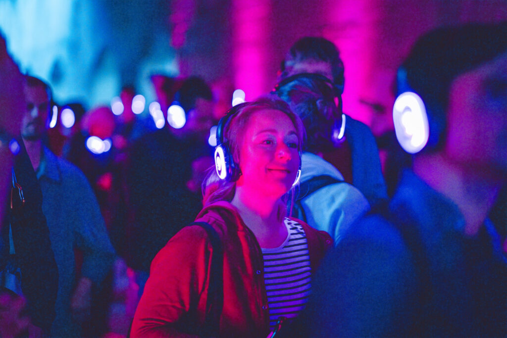 Eine Frau mit leuchtenden Kopfhörern beim Tanzevent: silent beat