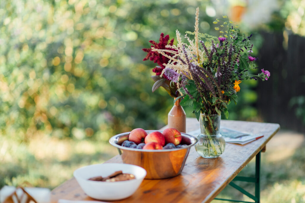 Wildblumen und Obst stehen auf einem Tisch im Garten der Malzfabrik.