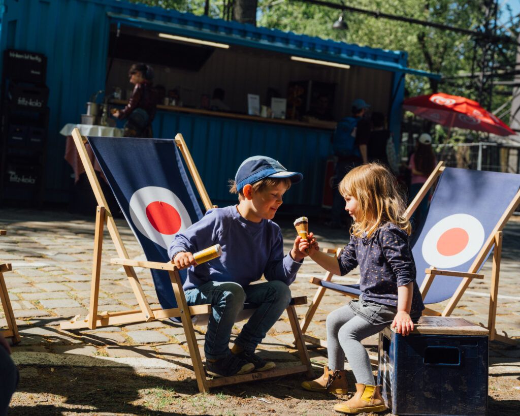 Kinder essen Eis und sitzen in Liegestühlen.