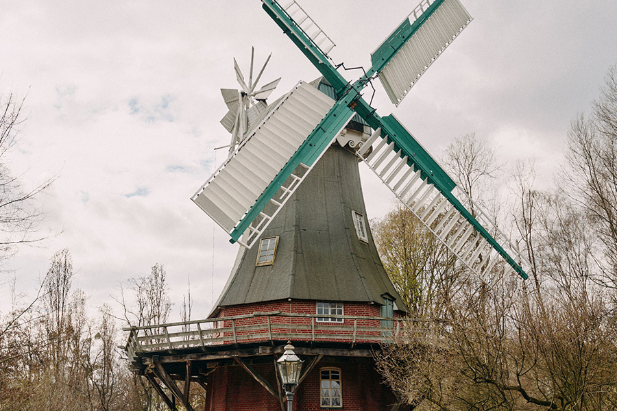 Eine Windmühle mit weißen Segeln, umringt von Bäumen im Herbst.