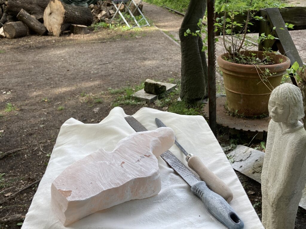 Pfeile und Raspel liegen neben einem Alabasterstein.