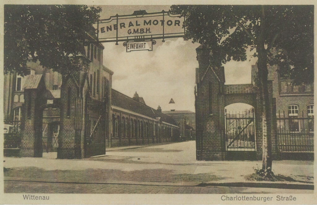 Historische Postkarte in schwarz-weiß. Blick auf das Eingangstor zum Werksgelände.