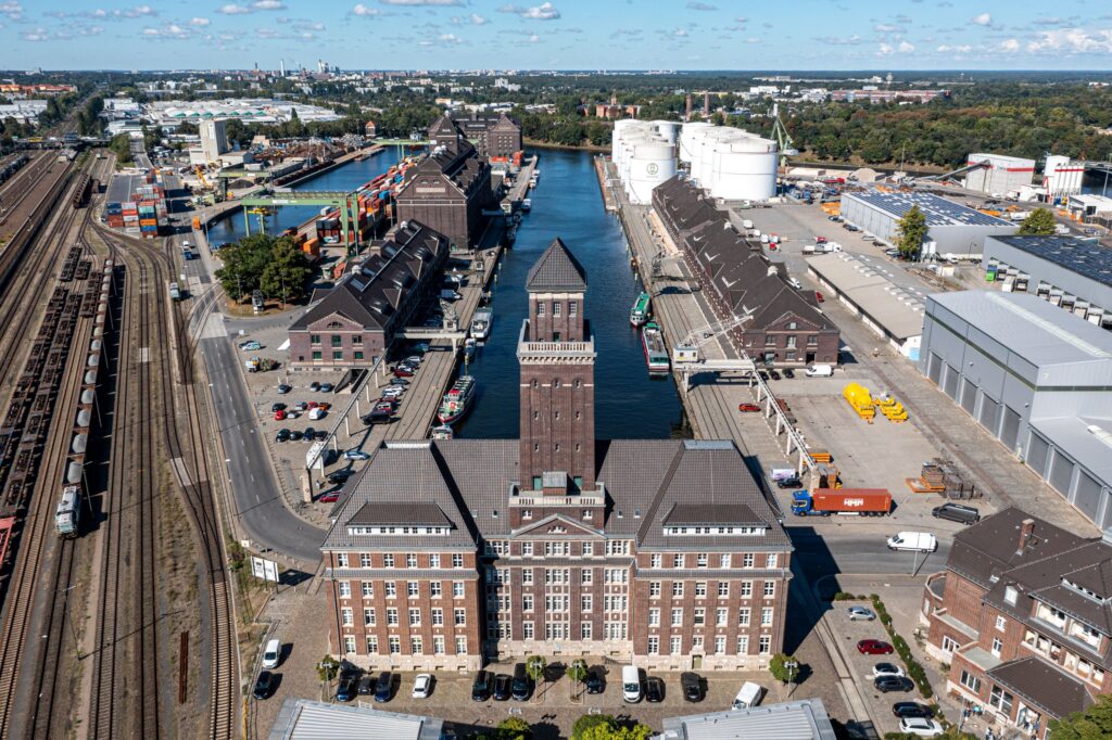 Luftbild auf den Westhafen mit Schienen, Gebäuden und Hafenbecken.