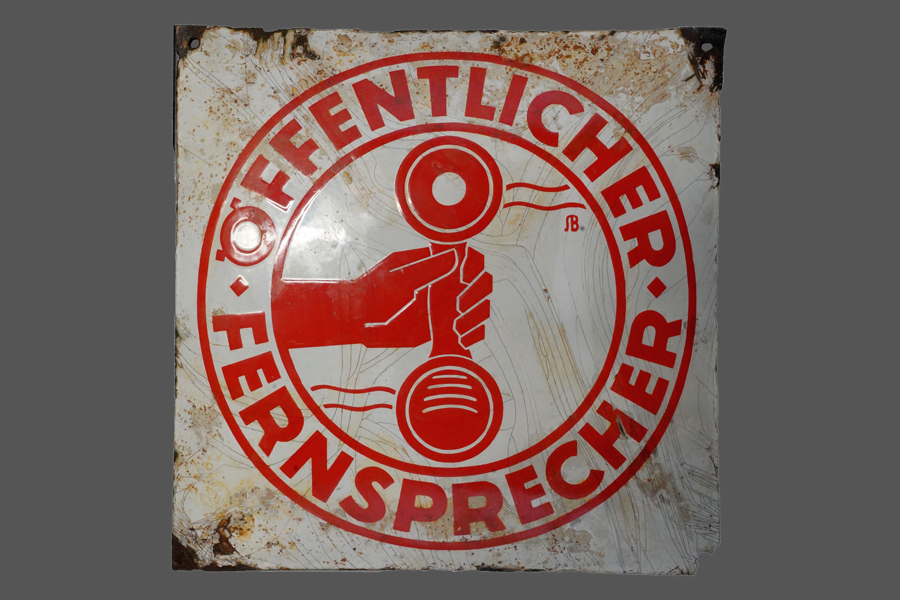 Weißes Emaille-Schild mit der roten Aufschrift Öffentlicher Fernsprecher