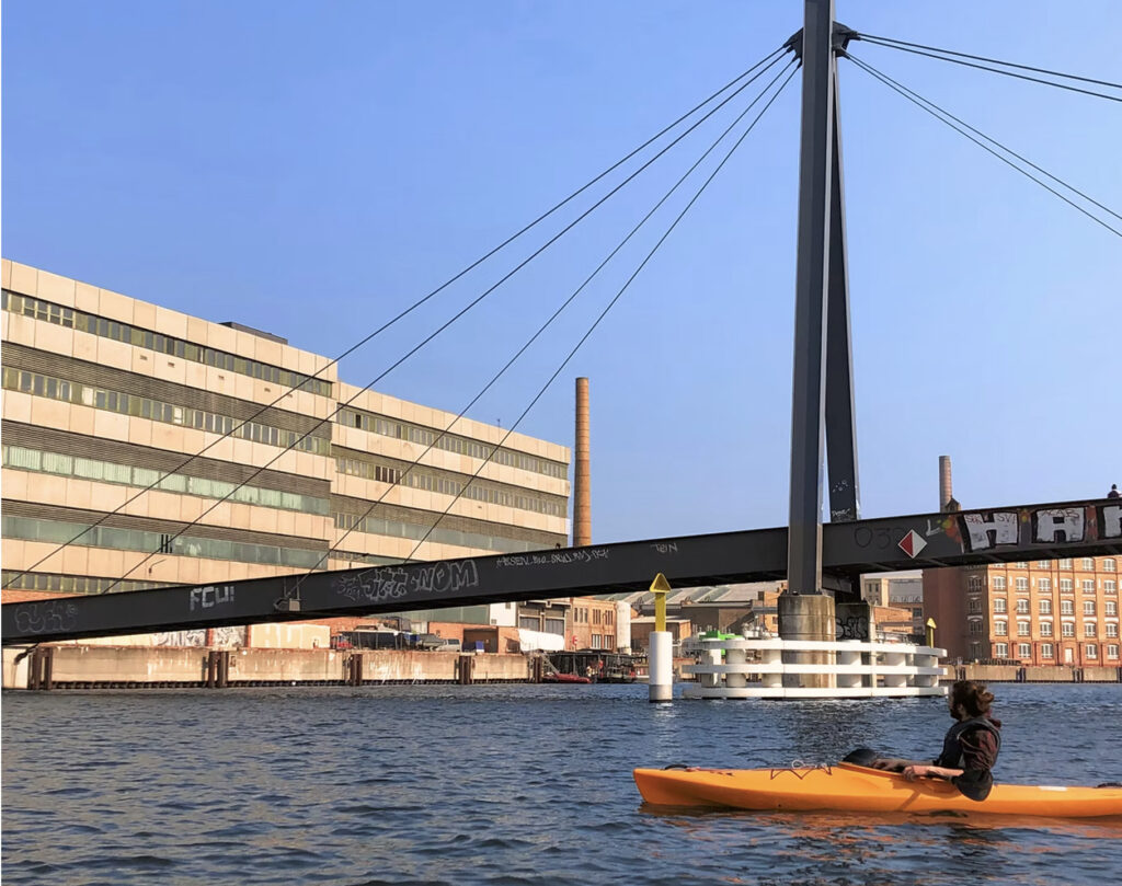 Ein Kanut paddelt auf der Spree unter einer Brücke entlang.
