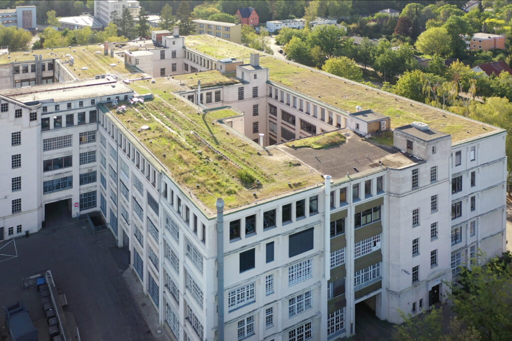 Luftbild auf ein großes Fabrikgebäude mit begrüntem Flachdach