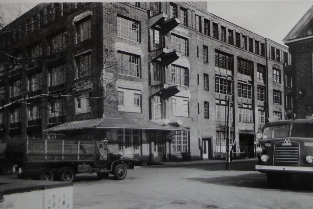 Lastfahrzeuge vor einem Fabrikgebäude mit flachem Dach historisches schwarz weiß Foto