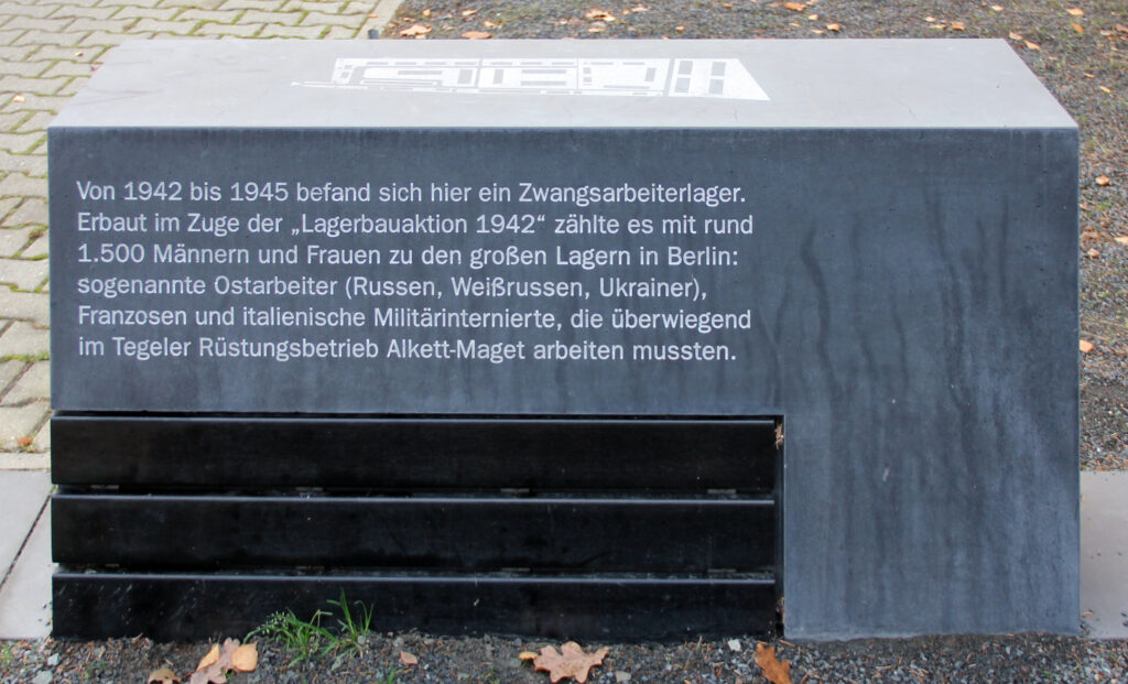 Betonbank am Gedenkort Krumpuhler Weg. Ein Text erklärt die Geschichte des Ortes. Auf der Sitzfläche ist ein Lageplan abgebildet.
