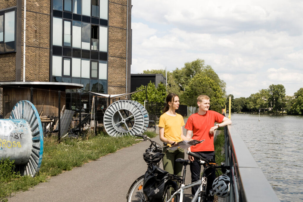 Fahrradroute »Wasser und Strom« | © Foto: Thomas Kierok Zwei Radfahrer auf der Route »Wasser und Strom« vor dem Kranhaus-Café in Oberschönweide. Blick auf die Spree.