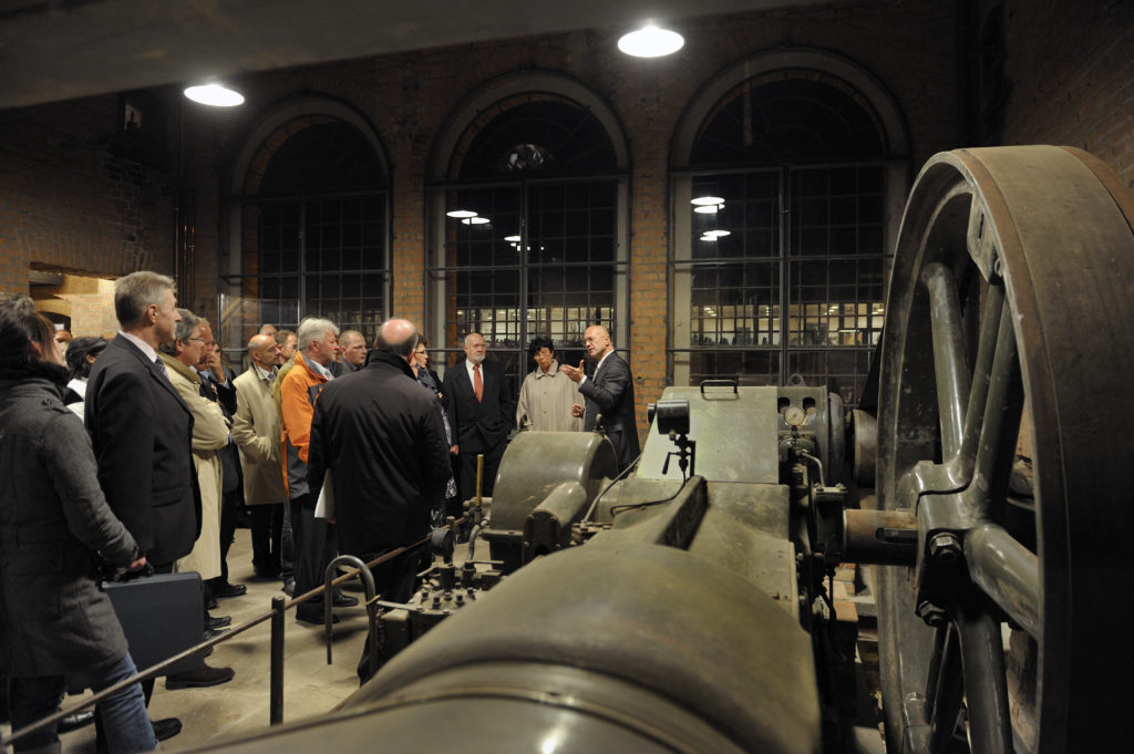 Dampfmaschine in der historischen Brennerei mit Besucher:innen