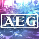 Logo der AEG, im Hintergrund das Foto einer historischen Fabrik zu sehen. Das Bild ist in Lila und Rosa eingefärbt.