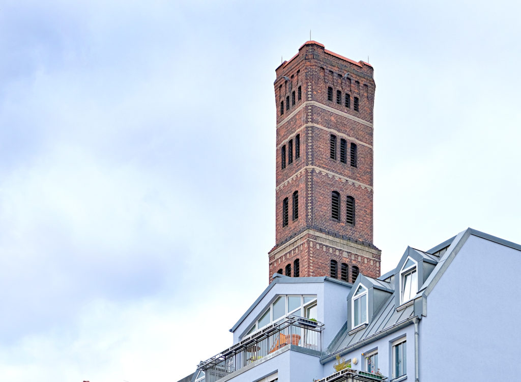 Schrotkugelturm hinter blauem Haus
