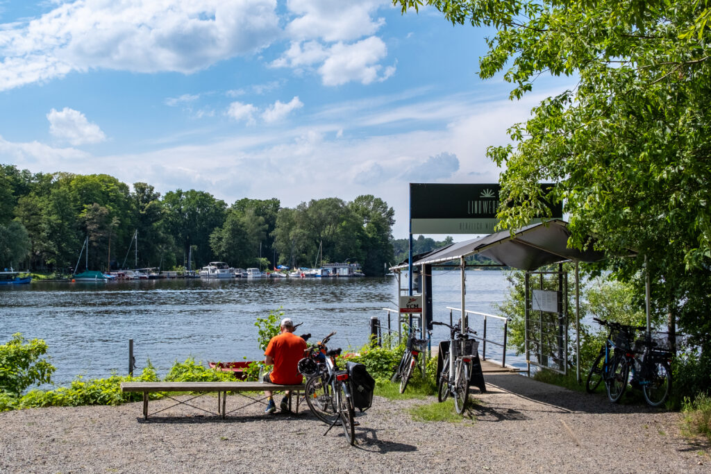 Ein Radfahrer, der in der Nähe des Stegs zur Fähre zur Insel Lindwerder auf einer Bank sitzt.