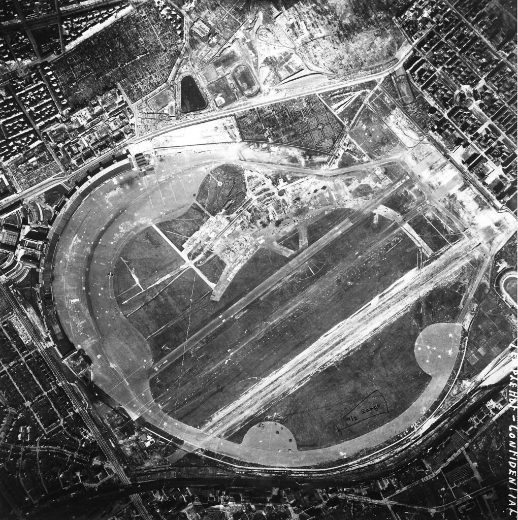 Eine historische Luftbildaufnahme in schwarz-weiß. Sie zeigt die ehemalige Ausdehnung des alten Flughafens.