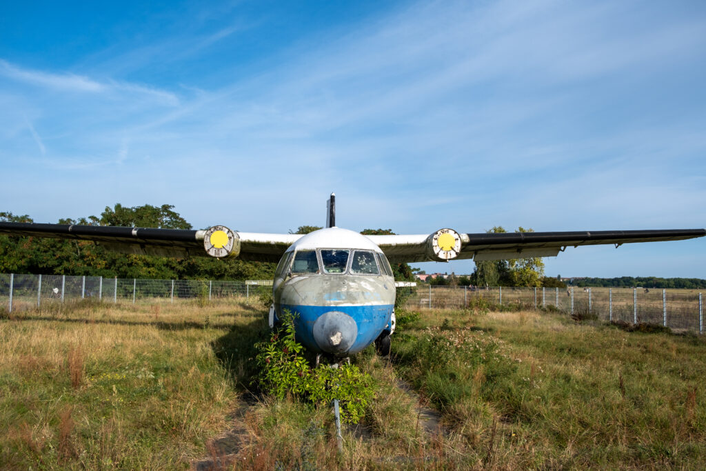 Frontale Aufnahme eines alten Flugzeugs im Gras. Witterungsspuren zeigen, dass es schon eine Weile nicht mehr in Benutzung ist.