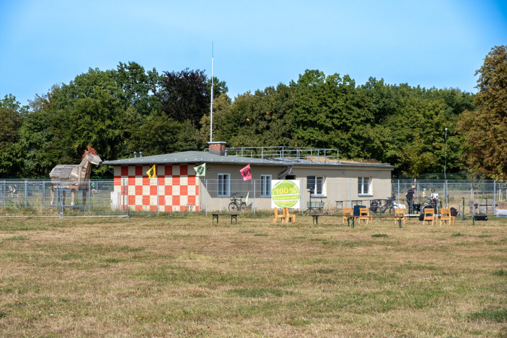 Das Foto zeigt die ehemalige Wetterstation, die jetzt als Bürgerhaus dient. Vor dem Haus stehen einige Stühle und es hängen bunte Fähnchen. Im Vordergrund des Hauses sieht man eine Rasenfläche, im Hintergrund Bäume und blauen Himmel.