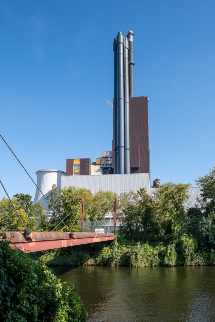 Außenansicht des Heizkraftwerks Lichterfelde. Im Vordergrund der Teltowkanal. Markant sind die hoch aufragenden Schornsteine.
